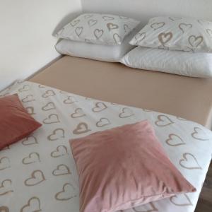 a bed with two pillows and a bedsheet with hearts at Stan-apartman A&A in Banja Luka