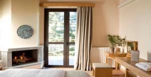 een slaapkamer met een open haard, een bed en een raam bij Natura Hotel Vytina in Vytina