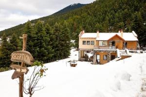 una casa en la nieve con un cartel delante en Natura Hotel Vytina, en Vitina