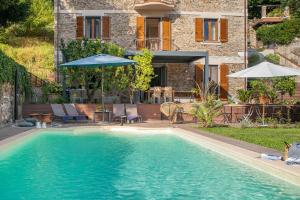 a swimming pool in front of a house with an umbrella at La Cava di Terzo in Antona