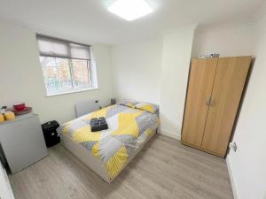a bedroom with a bed and a wooden cabinet at Lilleshall Rooms in Mitcham
