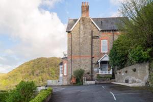 ein großes Backsteingebäude mit Parkplatz in der Unterkunft Highcliffe House in Lynton