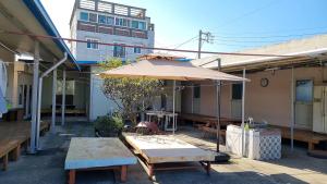 a patio with an umbrella and a table and benches at 돼지민박 102호 진하해수욕장 in Ulsan