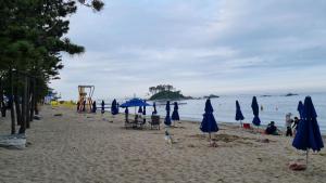 a beach with blue umbrellas and chairs and the ocean at 돼지민박 102호 진하해수욕장 in Ulsan