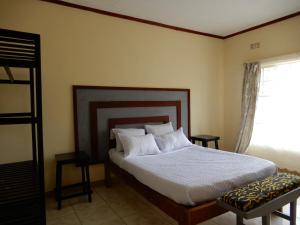 a bedroom with a bed with white sheets and a window at Quest in Lilongwe