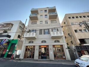 un grand bâtiment dans une rue avec une voiture garée devant dans l'établissement 2Bedroom Suite Allenby Hotel, à Tel Aviv
