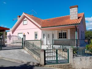 uma casa cor-de-rosa com uma vedação à frente. em PESO RIVER HOUSE em Melgaço