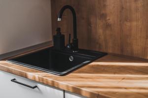a black kitchen sink on a wooden counter at VOYA NORDIC Apartment-a luxury oasis in the old town in Braşov