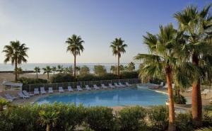 a swimming pool with lounge chairs and palm trees at Magnifique 4 pers plage à pied in Fréjus