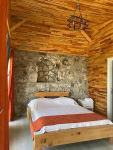 a bedroom with a bed in a stone wall at Ece Hanı Bungalow Hotel in Yaka