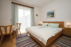 a bedroom with a bed and a chair and a window at Gästehaus Berger - Priglhof in Treffen