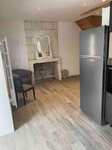 een woonkamer met een koelkast en een open haard bij Gîte Le Ballandeau in Ballan-Miré