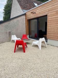 drie stoelen en een tafel voor een gebouw bij Gîte Le Ballandeau in Ballan-Miré