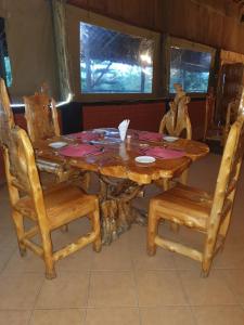 drewniany stół z 2 krzesłami i stół z płytami w obiekcie Masai Mara Explore Camp w mieście Narok