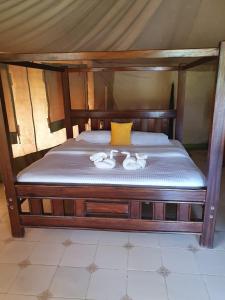 a wooden bed with two white towels on it at Masai Mara Explore Camp in Narok