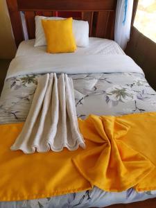a bed with a yellow and white blanket on it at Masai Mara Explore Camp in Narok