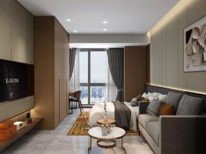 uma sala de estar com uma cama e um sofá em Shi Lai De Executive Apartments em Dongguan