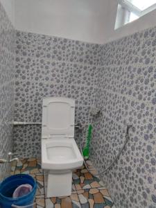 y baño con aseo en una pared de azulejos. en Beverly Hills Home stay, en Darjeeling