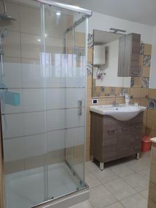 een badkamer met een glazen douche en een wastafel bij CASA ORCHIDEA in Carlentini