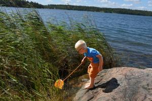 a young boy playing with a net on a rock by a lake at Sankt Anna Resort in Sankt Anna