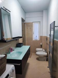een badkamer met een wastafel, een toilet en een spiegel bij Casa Vacanza Orchidea in Trieste
