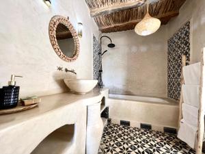 een badkamer met een wastafel, een bad en een spiegel bij Dar Salam Souss in Taroudant