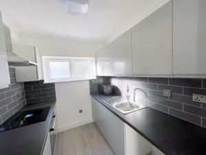 uma pequena cozinha com armários brancos e um lavatório em Exeter Road Rooms em South Norwood