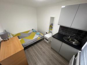 a small bedroom with a bed and a sink at Exeter Road Rooms in South Norwood