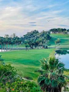 a golf course with palm trees and a lake at Casa de 3 plantas, con jardín y vistas al golf in Benalmádena