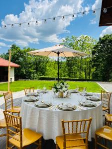 a table with a white table cloth and an umbrella at Agropensiunea Floare de Tei in Cărpiniş