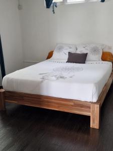 ein Bett mit weißer Bettwäsche und Kissen darauf in der Unterkunft Le Manguier in Mahébourg