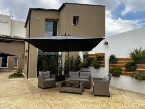 a patio with chairs and an umbrella in front of a house at L’angolo degli aromi in Ragusa