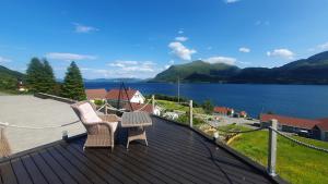 dos sillas y una mesa en un techo con un lago en Kvernesfjorden Apartments, en Averoy