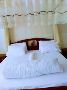 uma grande cama branca com lençóis e almofadas brancos em Kampala Ntinda Comfy Holiday Home em Kampala