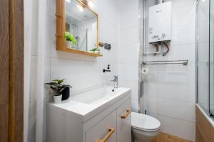 a white bathroom with a sink and a toilet at Kairos Apartments - City - darmowy Parking, ścisłe centrum in Katowice +16 photos