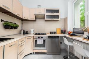 a kitchen with wooden cabinets and a stove top oven at Kairos Apartments - City - darmowy Parking, ścisłe centrum in Katowice