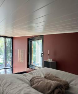 Ce lit se trouve dans une chambre dotée de murs rouges et de fenêtres. dans l'établissement Villa Kivi, à Valkeakoski