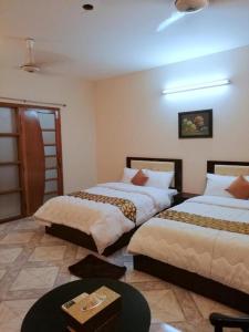 Cette chambre comprend 2 lits et une table. dans l'établissement Maple Crest Service Apartment, à Dhaka