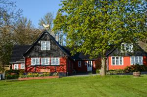 una casa roja con techo negro en Pyttegården Apartments, en Gudhjem