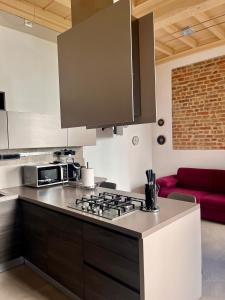 a kitchen with a stove and a red couch at Dimora Boezio7, cozy and charming place in center with private parking in Pavia