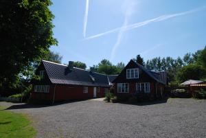 a red house with a driveway in front of it at Pyttegården Apartments in Gudhjem