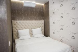 1 dormitorio con 1 cama con sábanas blancas y calaveras en la pared en Hotel VinoGrad en Haysyn