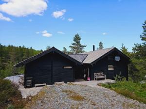 a black building with a bench in front of it at Special cottage in Sirdal in Tjørhom