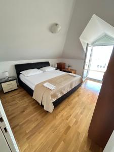 1 dormitorio con 1 cama grande y suelo de madera en Apartments Sanda 2, en Promajna