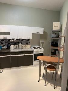 a kitchen with white cabinets and a wooden table at Whitchurch Shropshire Town duplex flat in Whitchurch