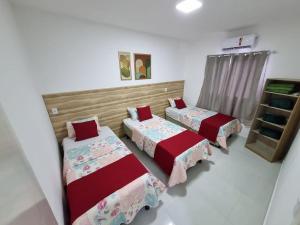 ein Schlafzimmer mit drei Betten und einem Regal in der Unterkunft Sobrado a 200m da Praia e Orla, 02 QTS com ar condicionado in Aracaju