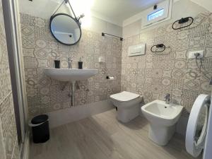 een badkamer met een wastafel, een toilet en een spiegel bij Unda Maris in Cisternino