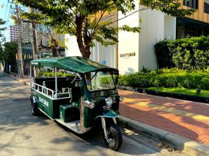 a small green vehicle parked on the side of a street at Craftsman Bangkok in Bangkok