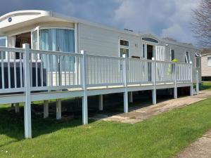 a mobile home with a porch and a white railing at The James Lodge in Little Clacton