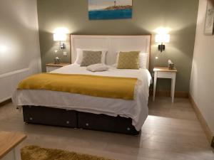 ein Schlafzimmer mit einem großen Bett mit zwei Tischen in der Unterkunft Quayside luxury apt Roundstoneselfcatering in Roundstone